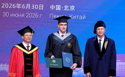 Absolvent s diplomami a profesormi na promócii v Pekingu.