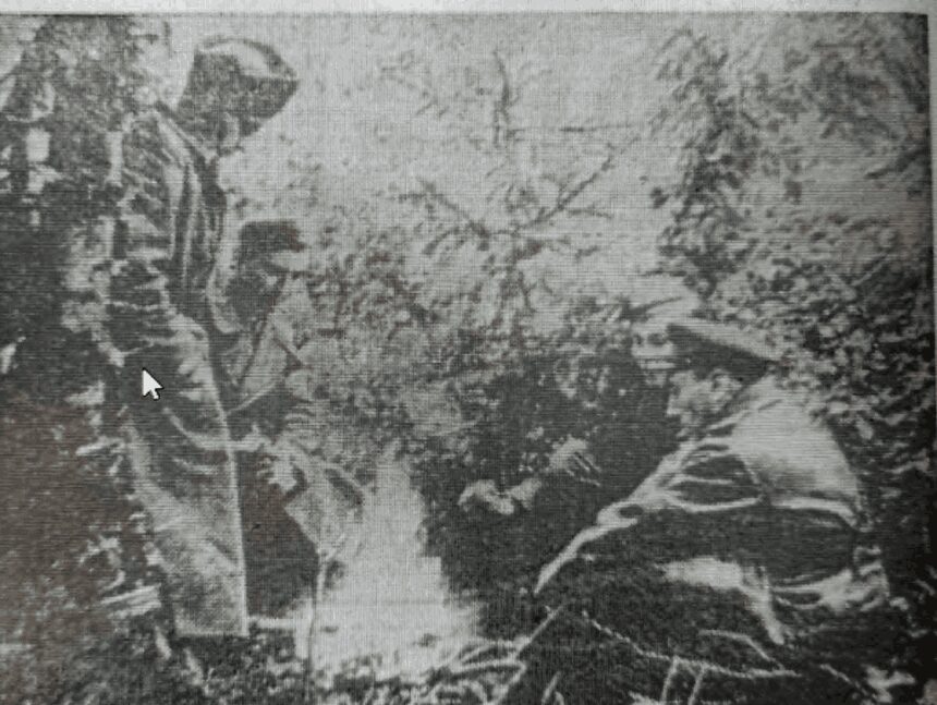 Historická čiernobiela fotografia partizánov v lese pri ohnisku