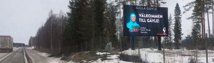 Islamizácia Švédska – pri vstupe do mesta Gävle visí billboard moslimky v hidžábe